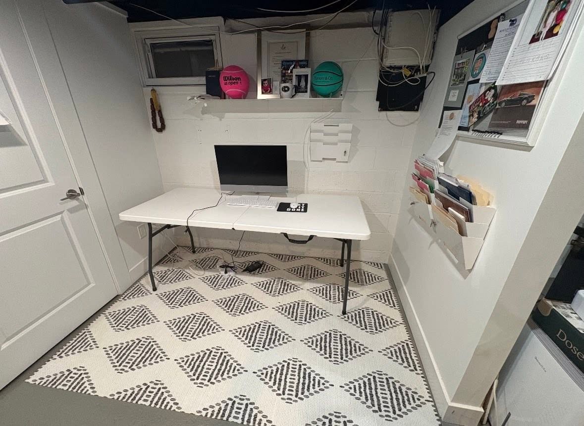 Finished basement office space with desk, computer, and patterned area rug