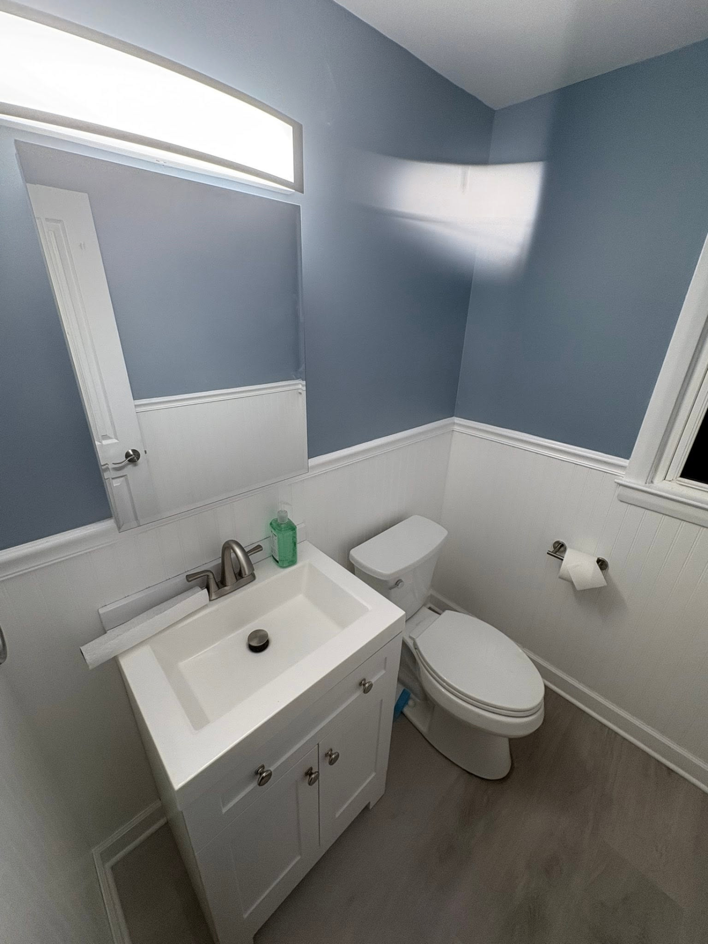Bathroom remodel with blue walls, white vanity, and updated trim details