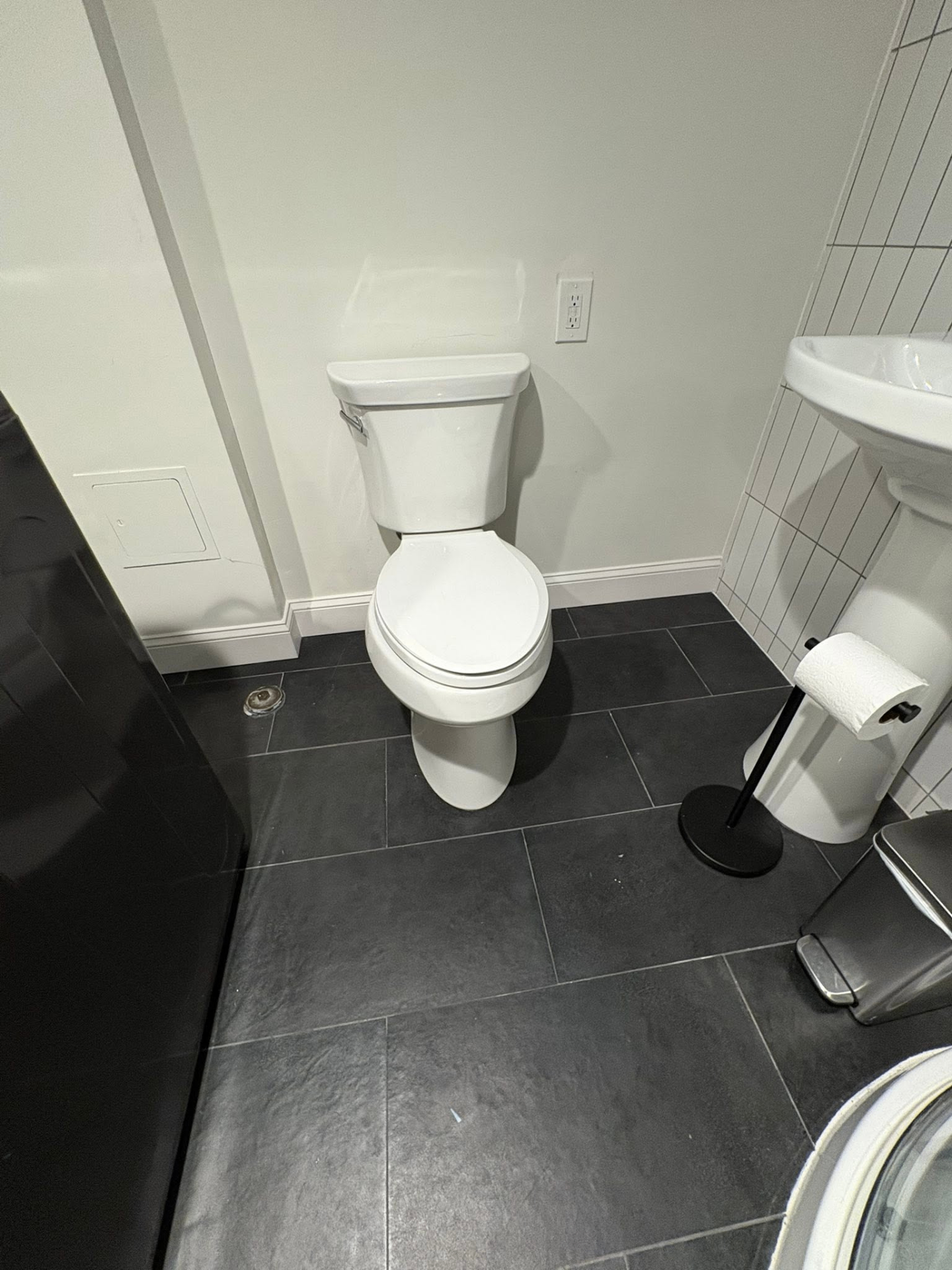 Modern bathroom with dark floor tile, clean white fixtures, and updated finishes