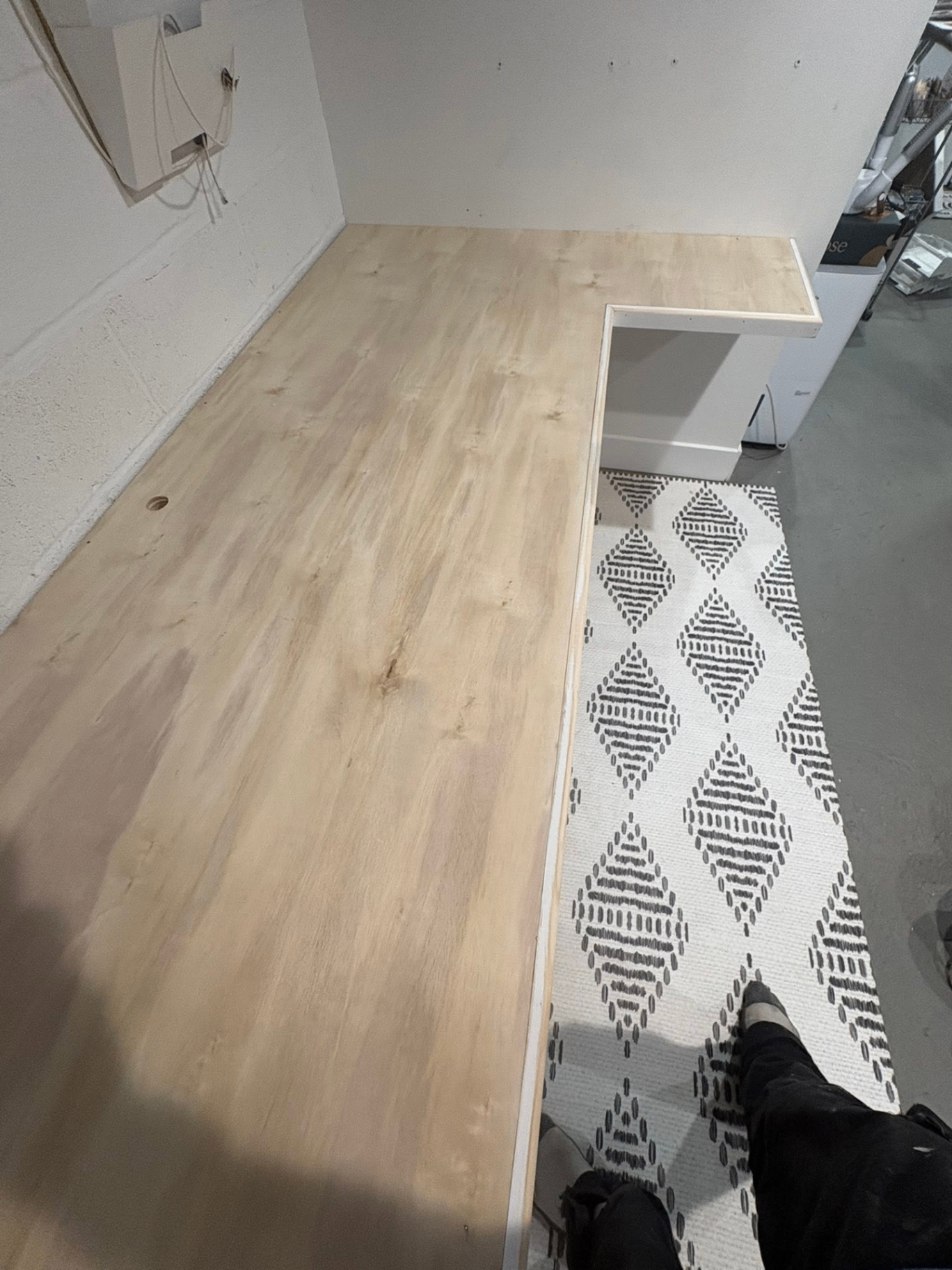 Custom built-in plywood shelf installed along a basement wall, mid-build